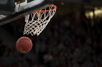 NBA篮球赛中球员飞身扣篮的精彩瞬间，体育馆内灯光聚焦，观众热情欢呼
